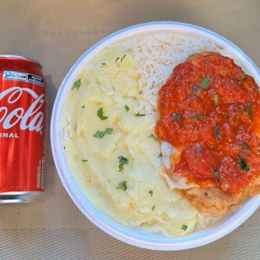 Marmita com delicioso filé de frango parmegiana (empanado na massa crocante coberto com molho de tomates e queijo) acompanhado de arroz branco e purê de batatas inglesas. Acompanha refrigerante lata Coca Cola 350ml bem gelada. Marmita indicada para 01 pessoa.