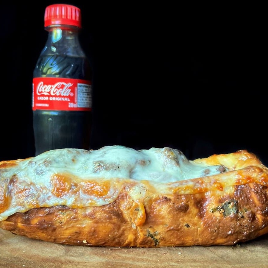 Pão de alho com uma generosa camada de pasta de alho com queijo e um espeto de carne.