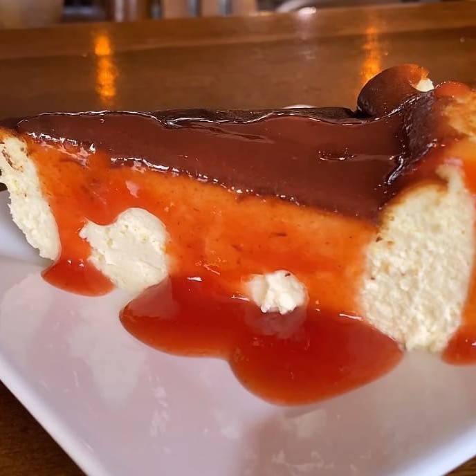 Cheesecake clássica espanhola: cremosa por dentro e dourada por fora, acompanhada de geleia de goiabada ou morango. Peça já