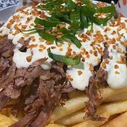 Batatas fritas cobertas com cupim desfiado coberta com mix de queijos derretidos e molhos.