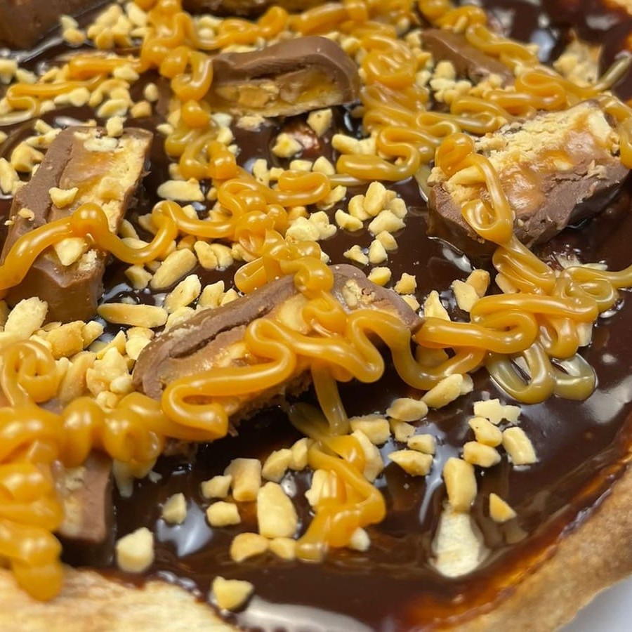 Ganache de chocolate ao blend, amendoim granulado, Snickers e fios de doce de leite.