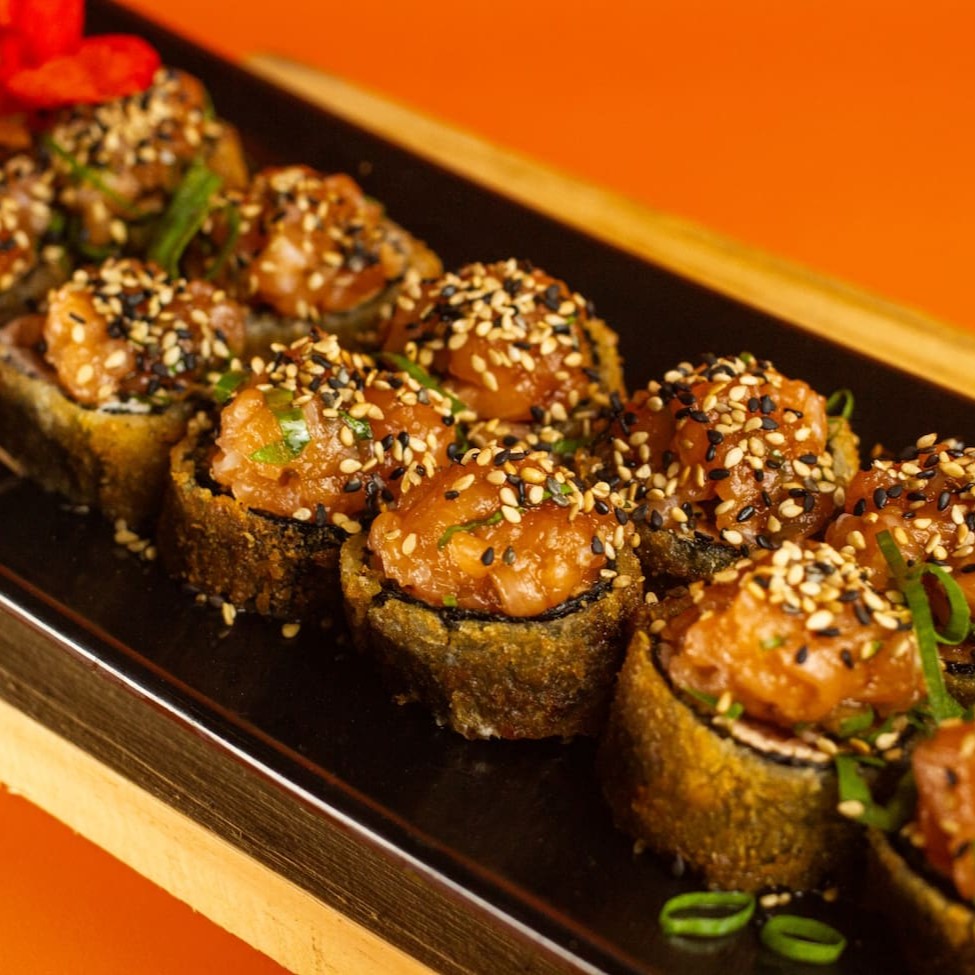 """Porção com 10 unidades de Hot Tartar, sushi empanado e crocante por fora, recheado com arroz temperado na medida certa e finalizado com uma generosa camada de tartar de salmão fresco temperado com especiarias orientais. Uma combinação que une cremosidade, frescor e crocância em cada mordida."""