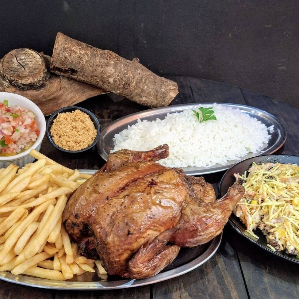 Frango assado e defumado, com sua característica coloração avermelhada da defumação, acompanhado de 500g de batata frita ou aipim frito, 500g de arroz, molho à campanha, farofa crocante de bacon e 500g de salpicão. Uma refeição completa e saborosa, perfeita para compartilhar!