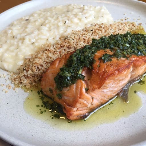 Salmão grelhado ao molho ervas com um cremoso risoto de limão siciliano acompanhado de uma farofinha de panko.