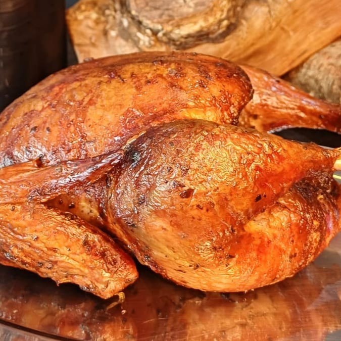 Um prazer defumado aguarda você com nosso frango assado na lenha frutífera, servido com uma farofa de bacon incrível.