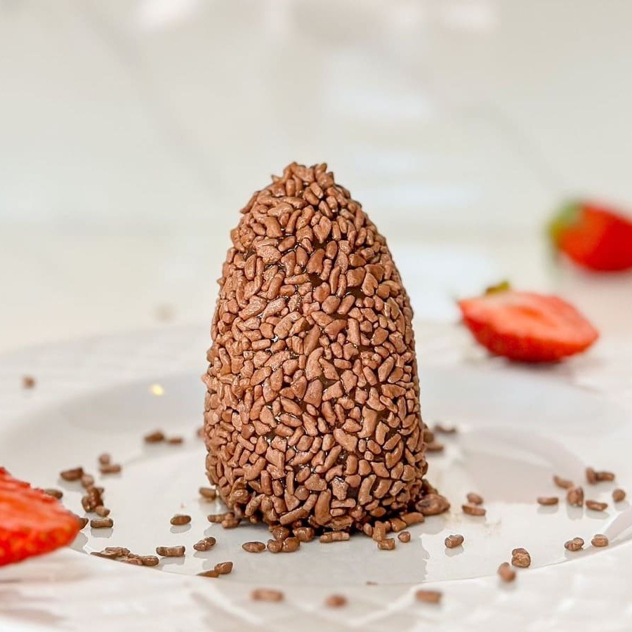 Apresentamos a nossa irresistível e inovadora 'Coxinha de Brigadeiro com Morango', uma delícia que faz parte da nossa categoria 'Paixão por Coxinhas!'. Este doce primorosamente elaborado apresenta uma generosa camada de sedoso e rico brigadeiro de chocolate, recheada com um coração suculento de morango fresco. Uma combinação perfeita de sabores que promete agradar o paladar mais exigente. Experimente e se apaixone por essa explosão de sabor!