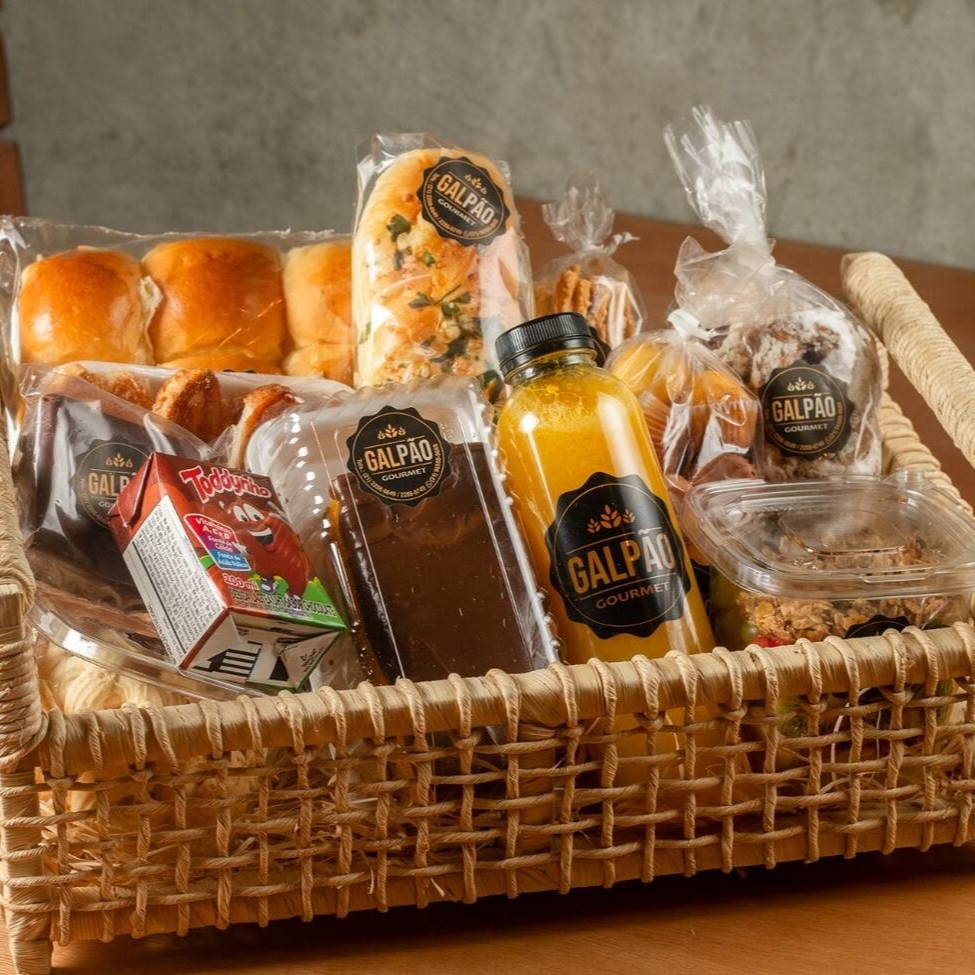 Uma cesta especial para alegrar deliciosamente o Dia de quem você mais ama!  Cesta tamanho média  1 Suco de laranja 500ml  1 Salada de Frutas 1 Bolo laranja sem lactose - 250g 1 Pct de Brioche Tradicional - 6un 1 Pão de Mel Galpão 1 Pct Rosca Penha 130g 1 Pct Palitinho de Queijo 140g 1 Pct  Mini mãe benta 140g 1 Bandeja de Palmier com 6un 1 Toddynho 200ml  1 Croissant (Não recheado) 1 Pct Amanteigado de Nata 150g   Obs: Em caso de indisponibilidade de algum item, este será substituído por outro de valor equivalente ao em falta. A cesta possui uma quantidade máxima especificada acima.  Imagem Ilustrativa