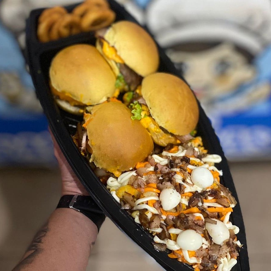 Pão brioche,  carnes, ovo, presunto, queijo,  fatias de cheddar, cream cheese, bacon e molho.