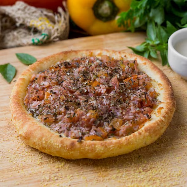 Esfiha de Pizza, meticulosamente preparada com a autêntica mussarela que derrete na boca, presunto de alta qualidade, suculentos tomates frescos e orégano aromático para adicionar aquele toque especial.