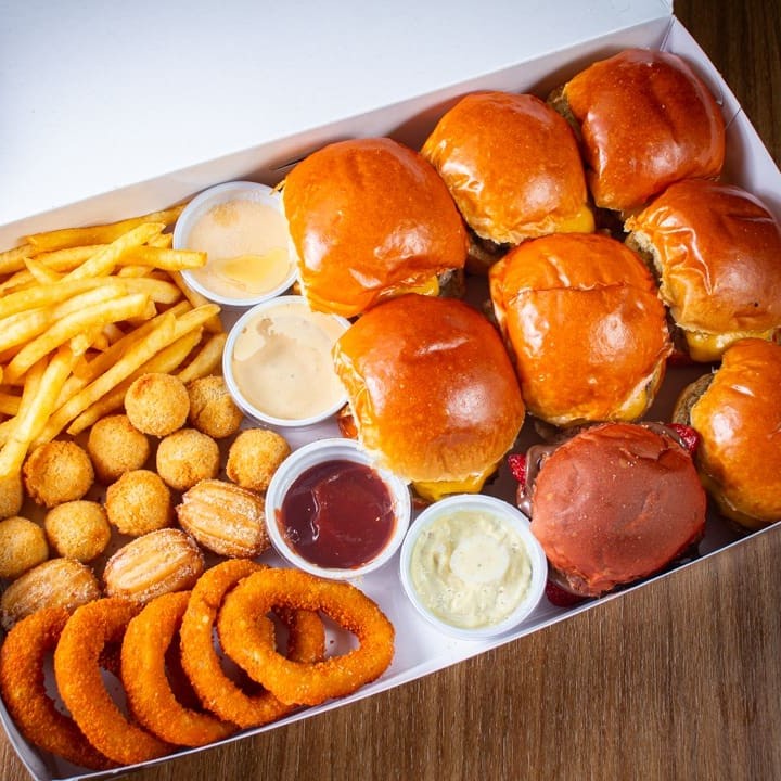 Nosso rodízio em casa é um grande sucesso. Nossa caixa "Mágica" carinhosamente chamada, pois leva uma grande alegria ao chegar na sua casa.  São 8 miniburguers - você escolhe os sanduíches e monta do seu jeito.  4 opções de frituras - Porções. 01 porção de Batata - 120g 01 porção de Anel de cebola - 5 unidades  01 porção de Nuggets - 5 unidades  01 porção de Mini churros - 3 unidades  4 opções de molho a sua escolha.