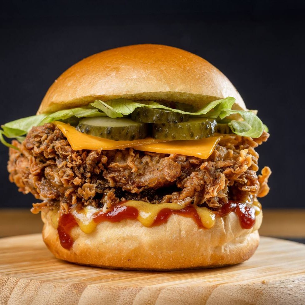 Releitura do famoso burger do palhaço! Filé de sobrecoxa crispy (ou 2 filezinhos de peito), queijo cheddar derretido, alface crocante, picles, cebola, ketchup e mostarda no pão brioche macio. Sabor em camadas que vai fazer você querer repetir!