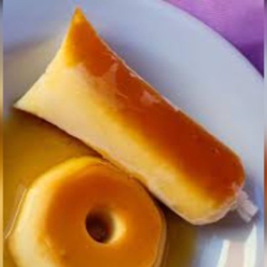 O sacolé de pudim com calda de caramelo é uma sobremesa gelada irresistível que combina a cremosidade do pudim com a refrescância do sacolé. Ele é feito com uma base rica e aveludada reproduzindo o sabor clássico do pudim de leite. A calda de caramelo, dourada  adiciona um toque de doçura intenso e um aroma delicioso. Ao congelar, o sacolé ganha uma textura firme por fora, mas ao ser saboreado, derrete na boca, revelando sua cremosidade e o contraste perfeito entre o caramelo e o pudim. É uma versão inovadora e prática do tradicional pudim brasileiro, perfeita para dias quentes!