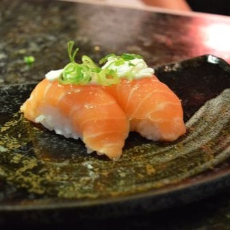 Sushi Salmão com cream cheese em cima e cebolinha.
