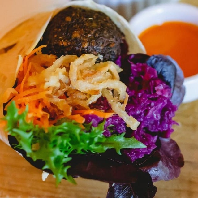 Pão folha, falafel, homus, acelga, cenoura, picles de repolho roxo, cebola frita e tahine