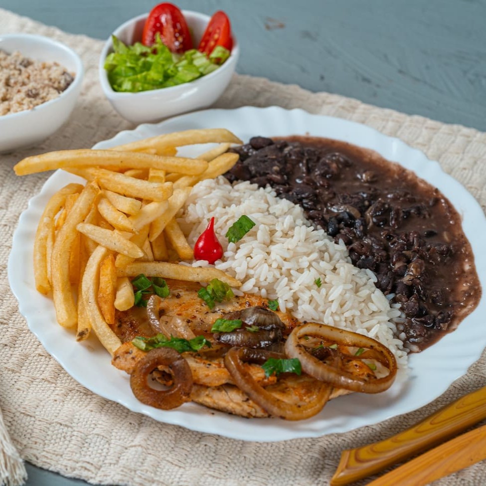 Filé de frango grelhado no ponto perfeito, suculento e temperado com carinho. Acompanha arroz soltinho, feijão caseiro bem temperado, batatas fritas crocantes, farofa dourada e uma salada fresquinha para equilibrar os sabores. Uma refeição leve, saborosa e nutritiva para qualquer momento!