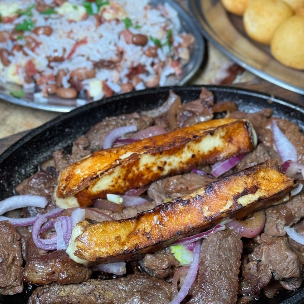 Aproximadamente 380g de carne de sol acebolada com bolinhas de aipim frito. Acompanha arroz baião de dois, queijo coalho, molho e farofa.