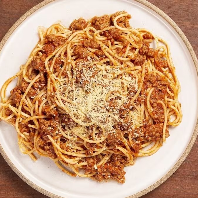 Massa al dente coberta com um molho bolonhesa artesanal rico em sabor, feito com carne moída selecionada, finalizado com queijo parmesão ralado e azeitonas fatiadas. Um clássico italiano com o toque irresistível da casa!