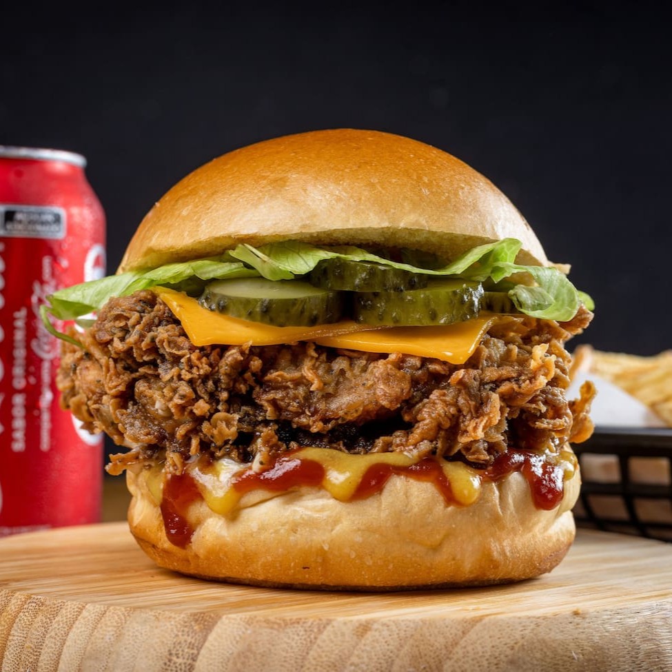 Releitura do famoso burger do palhaço! Filé de sobrecoxa crispy (ou 2 filezinhos de peito), queijo cheddar derretido, alface crocante, picles, cebola, ketchup e mostarda no pão brioche macio. Acompanha batata P crocante e 1 bebida gelada. Sabor em camadas que vai fazer você querer repetir!