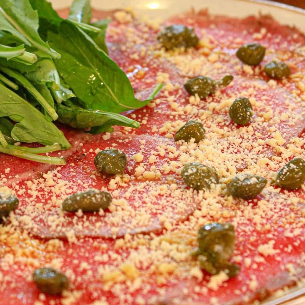 Carpaccio de carne, alcaparra, rúcula e parmesão. Acompanha torradas de focaccia.