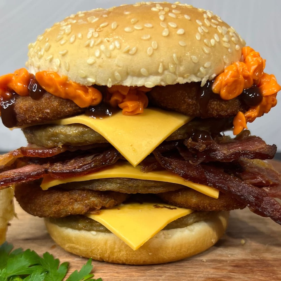 Pão, 3 carnes, 3 fatias de queijo, 4 anéis de cebola empanado, 3 fatias de bacon, cheddar cremoso em dobro e molho barbecue.