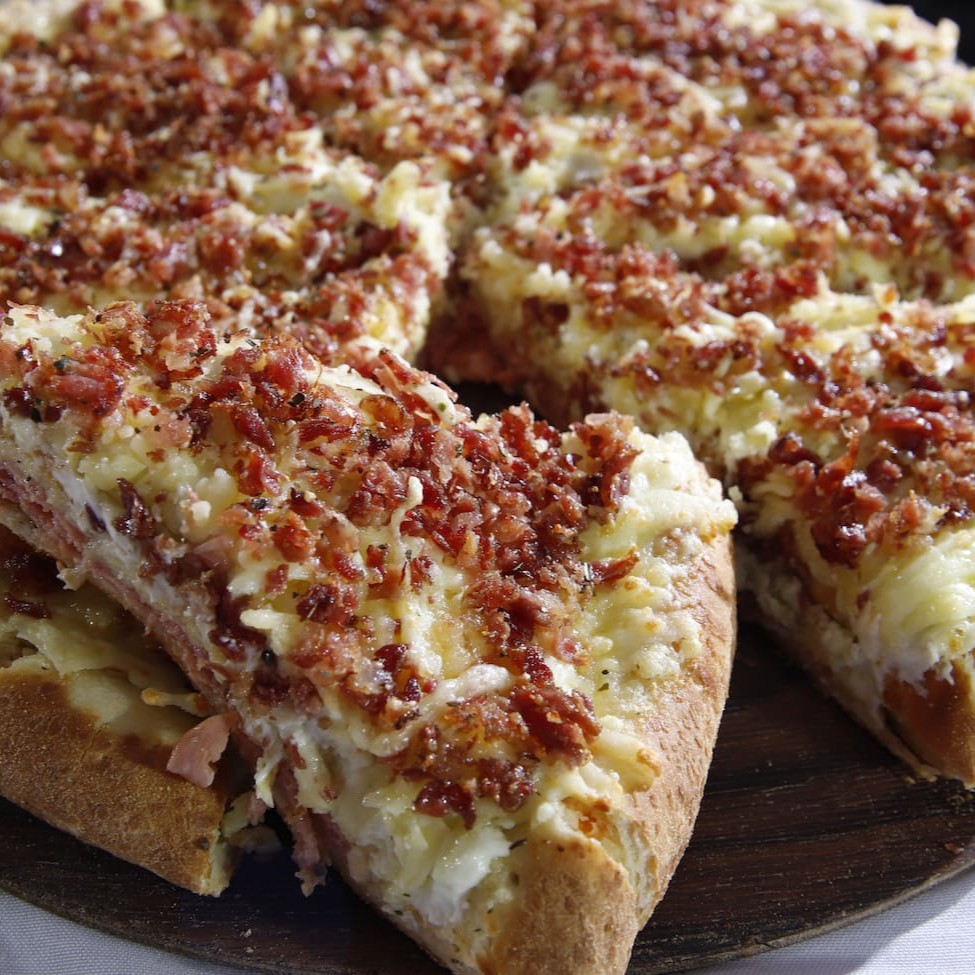 Uma deliciosa pizza de 2 andares, que serve de 2 a 4 pessoas. 1º And. Molho; Atum; Muçarela 2º And.: molho especial; provolone; parmesão; Bacon e Orégano Borda: Muçarela; Requeijão e Cheddar.