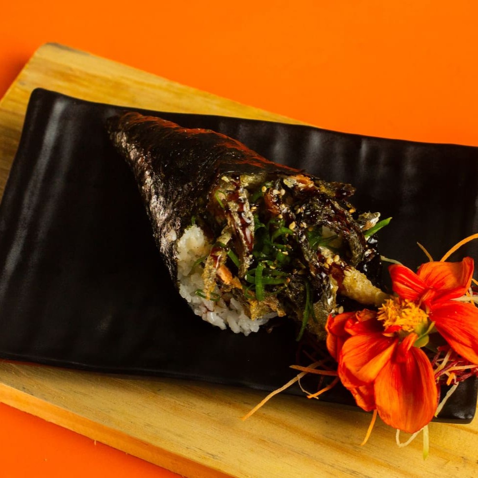 """Temaki Skin feito com alga crocante, arroz temperado e generosa porção de pele de salmão grelhada até ficar dourada e levemente crocante. Finalizado com cream cheese cremoso para equilibrar o sabor e trazer suavidade, é enrolado na hora para garantir frescor e textura perfeita. Uma combinação deliciosa que conquista desde a primeira mordida."""