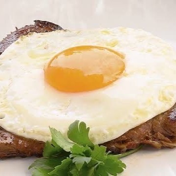 Apresentamos o clássico 'Bife à Cavalo', a opção perfeita para os amantes de carne. Este prato é composto por um suculento bife, cuidadosamente grelhado para preservar o sabor e a maciez da carne. Acompanha arroz fresquinho e feijão, preparado com temperos selecionados que acentuam seu sabor autêntico. Para completar, um ovo frito, com a gema ainda mole, que adiciona uma textura cremosa à refeição, e batatas fritas crocantes e douradas. Uma refeição robusta e deliciosa que vai te satisfazer!