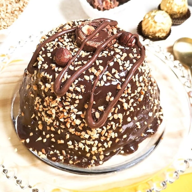 Incomparável bolo composto por uma massa de chocolate, recheio de creme de avelã, cobertura de brigadeiro gourmet de chocolate, finalizado com castanha de caju, fios de creme de avelã, duas avelãs e Ferreiro Rocher.