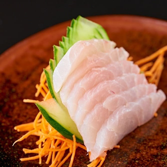 O sashimi de peixe branco é um prato típico da culinária japonesa, composto por fatias finas de tilapia cru e fresco, servido com molho shoyu e wasabi.