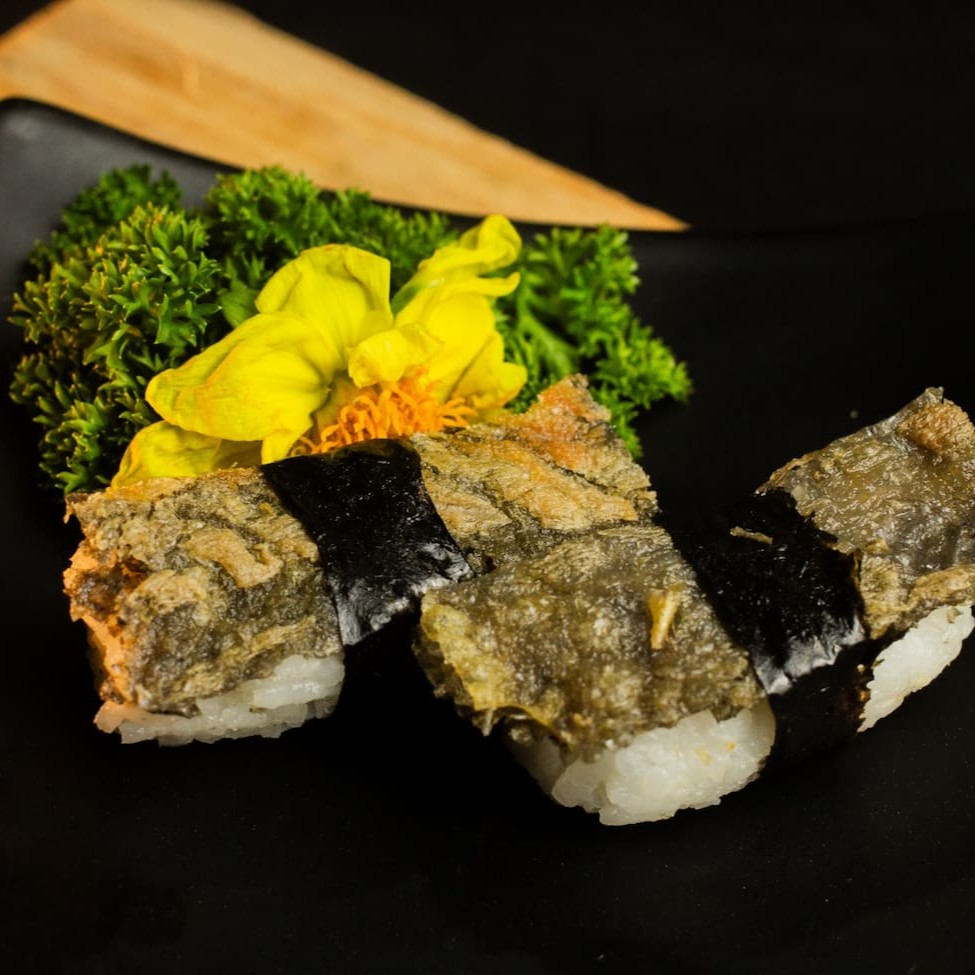 """Porção com 4 unidades de sushi skin, preparados com arroz temperado e cobertos com pele de salmão grelhada até ficar dourada e crocante. Uma combinação de texturas irresistíveis, que une o sabor marcante da pele crocante com a suavidade do arroz, proporcionando uma experiência única e saborosa."""