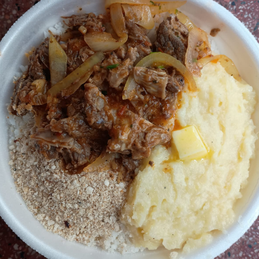 Sendo: 80 gramas de feijão, 200 gramas de arroz, 70 gramas de purê de batata com queijo ou macarronada, potinho de salada, farofa e 100 gramas de costela bovina acebolada