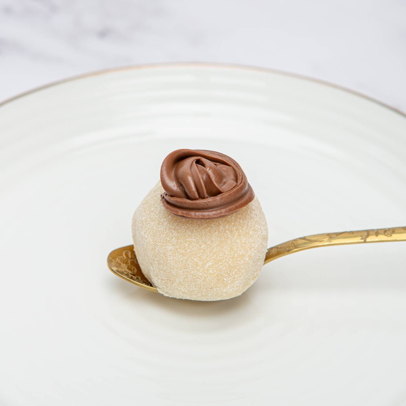 Brigadeiro de ninho recheado com brownie chocolatudo, finalizado com roseta de avelã.