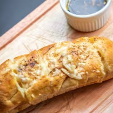 Pão de alho crocante, recheado com manteiga de alho e ervas, perfeito para compartilhar e abrir o apetite.