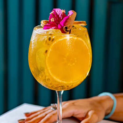 Dose de Gin Tropical, energético e fruta (opcional).