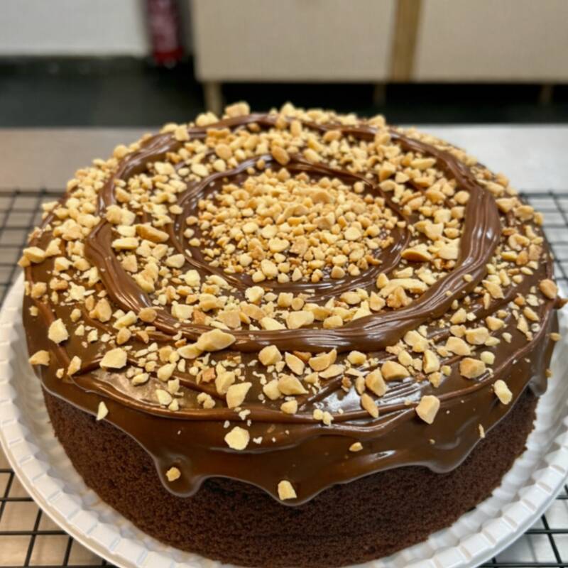 Massa fofinha de chocolate recheado e com cobertura de brigadeiro ao leite cremoso com fios de nutella e amendoim granulado