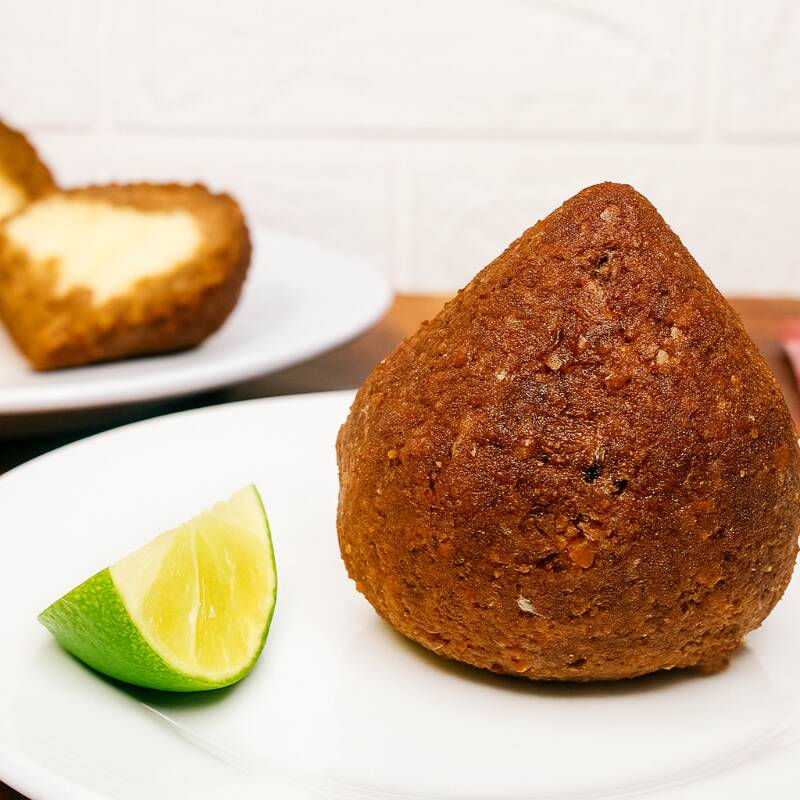 Com alma de quibe e corpo de coxinha, a Quibexinha é a fusão perfeita entre tradição e ousadia. Sua massa suculenta, feita com trigo para quibe e carne moida, temperada na medida certa, é moldada no formato mais amado do Brasil. O recheio? Um irresistível creme de queijo feito com mozarela e requeijão, que derrete na boca e surpreende a cada mordida. Crocante por fora, cremosa por dentro — a Quibexinha é mais que um salgado: é uma experiência.