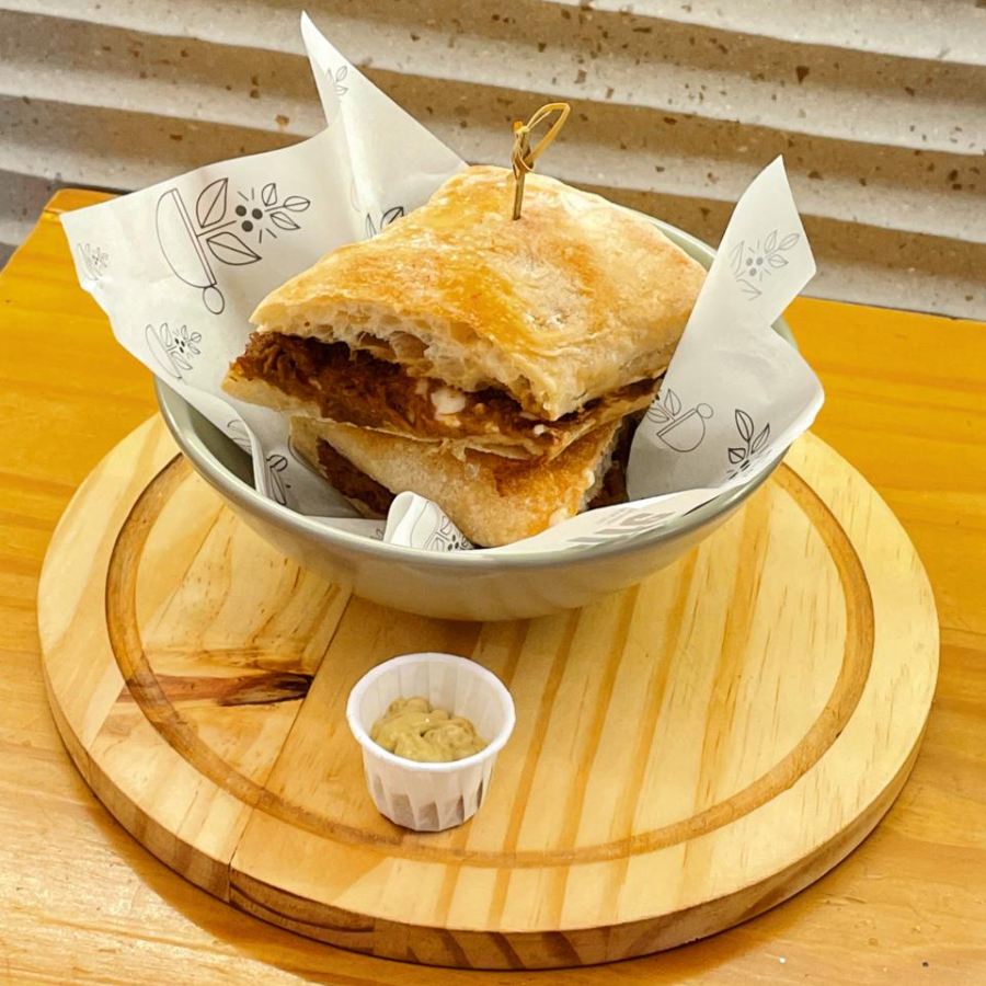 Pão ciabatta de fermentação natural, recheado com carne de panela ao molho de cerveja preta e creme de três queijos. Acompanha molho de mostarda e maracujá.