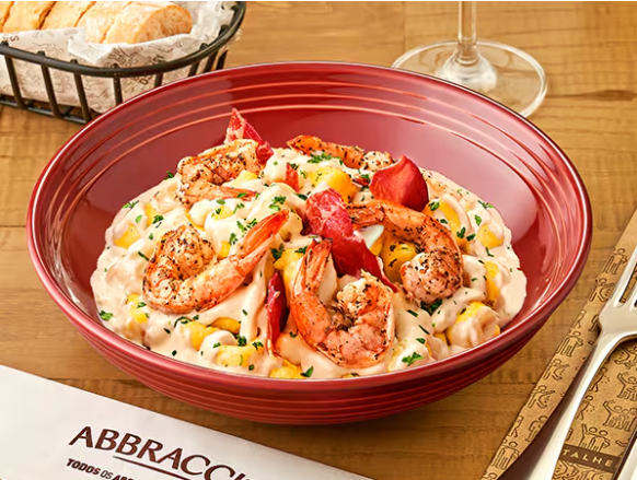 Gnocchi de massa fresca de batatas, feito à mão em nossa cozinha, servido ao cremoso molho de parmesão Faixa Azul com um toque de camarão, acompanhado de camarões frescos grelhados e finalizado com prosciutto crocante.