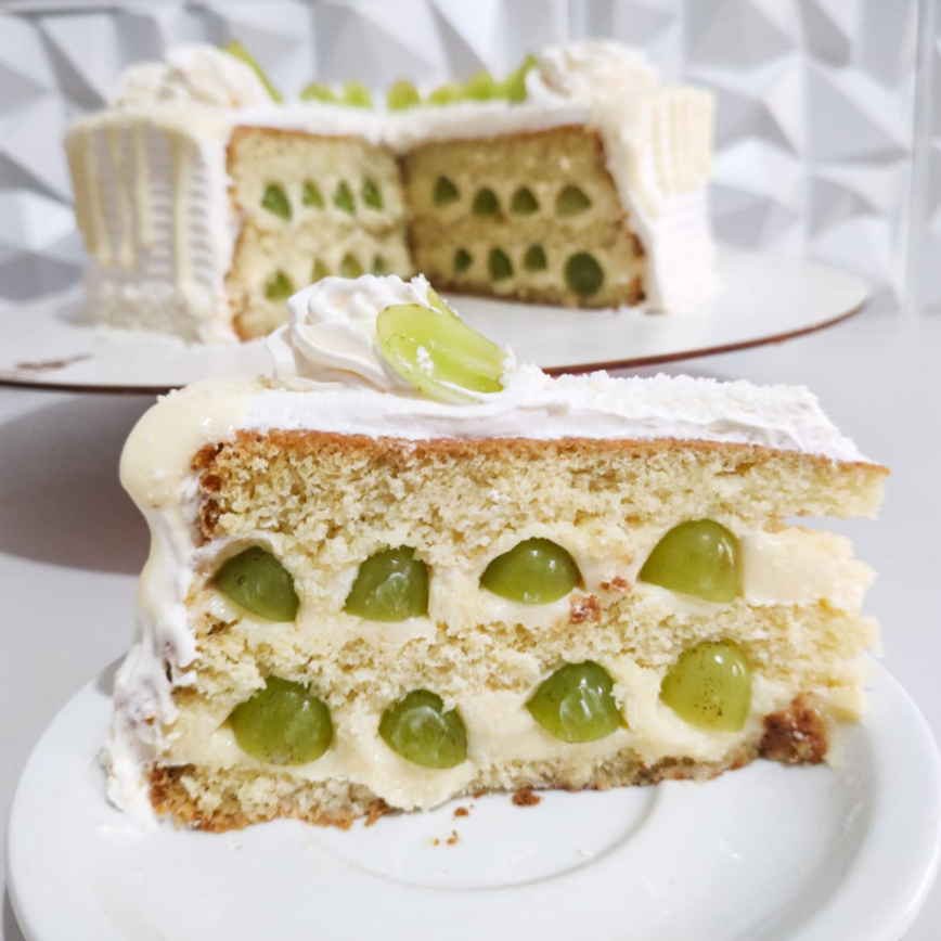 Fatia de Torta Surpresa de Uva com Ninho: massa fofinha de baunilha, creme de Ninho super cremoso e uvas frescas que deixam cada mordida doce, leve e refrescante. Uma fatia generosa, geladinha e perfeita para se apaixonar no primeiro pedaço.