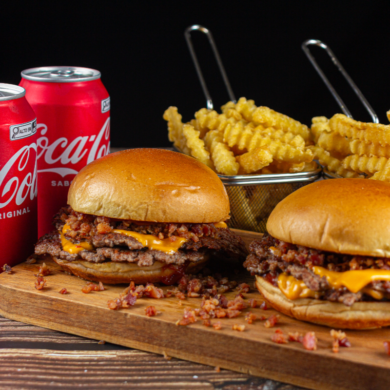 2 deliciosos hambúrgueres artesanais Duplo Bacon no estilo smash burguer + Batata Frita de 100g cada e 2 refrigerantes Coca-Cola geladinho para completar esse combo.