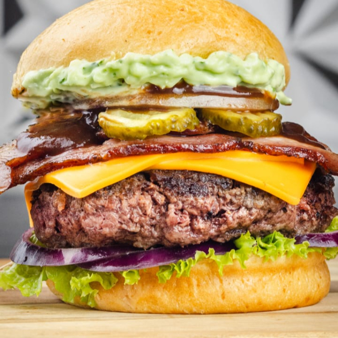 Pão Brioche, Hamburguer de 130g, mussarela, bacon, barbecue, molho verde, cebola roxa e salada.