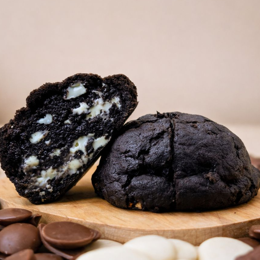 Um cookie que conquista no primeiro olhar e na primeira mordida: massa amanteigada de cacau black, crocante por fora e macia por dentro, recheada com generosos pedaços de chocolate branco que derretem suavemente. O contraste perfeito entre a intensidade do cacau e a doçura cremosa do chocolate branco. Uma combinação irresistível que vai deixar você com vontade de pedir mais de um!