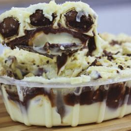 Delicioso Pavê de Bombom Ouro Branco, com camadas intercaladas de biscoito maizena e recheios cremosos de chocolate branco e preto. Finalizado com bombom Ouro Branco picado e um bombom Ouro Branco inteiro. Com seu peso aproximado de 700g.