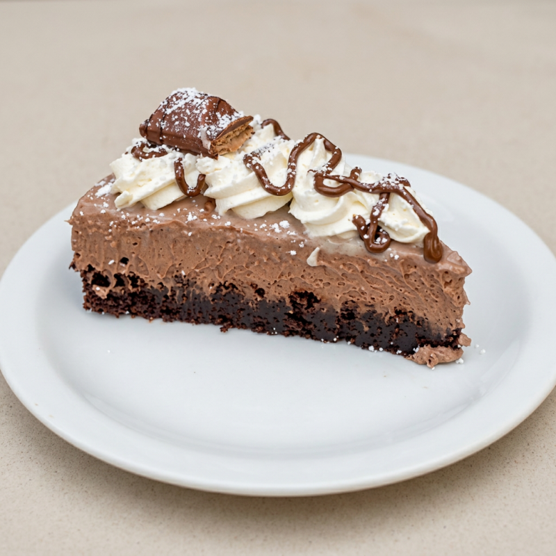 Aprimore o seu paladar com a nossa Torta Brownie de Kinder Bueno, uma iguaria da categoria Bolos & Tortas. Ela é primorosamente preparada com uma base irresistível de brownie macio e rico em sabor. Uma camada de mousse trufado de chocolate meio amargo, intenso e cremoso, envolve a base para proporcionar uma experiência sensorial única. A coroação desse deleite se dá com um sublime creme de chocolate branco, que adiciona um toque suave e sofisticado ao conjunto. Este doce, sem dúvida, é uma combinação celestial que agrada até os paladares mais exigentes.