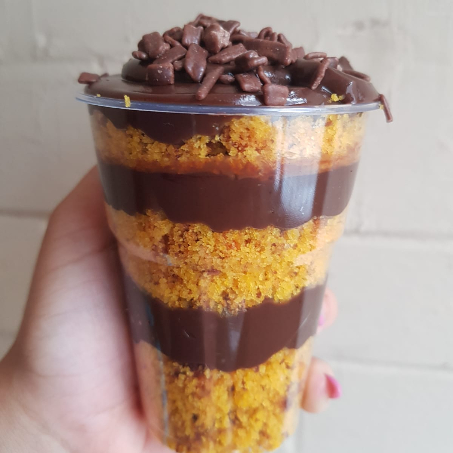 Copo da felicidade com um bolo fofinho de cenoura com camadas de um delicioso brigadeiro de chocolate 50%, finalizado com granulado.