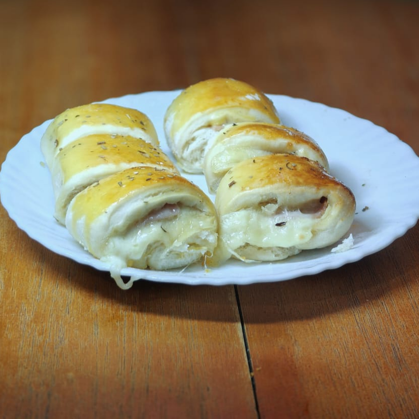 6 unidades de Mini joelho assado, recheado com queijo derretido e presunto, massa macia e douradinha. Um lanche clássico que agrada todo mundo.