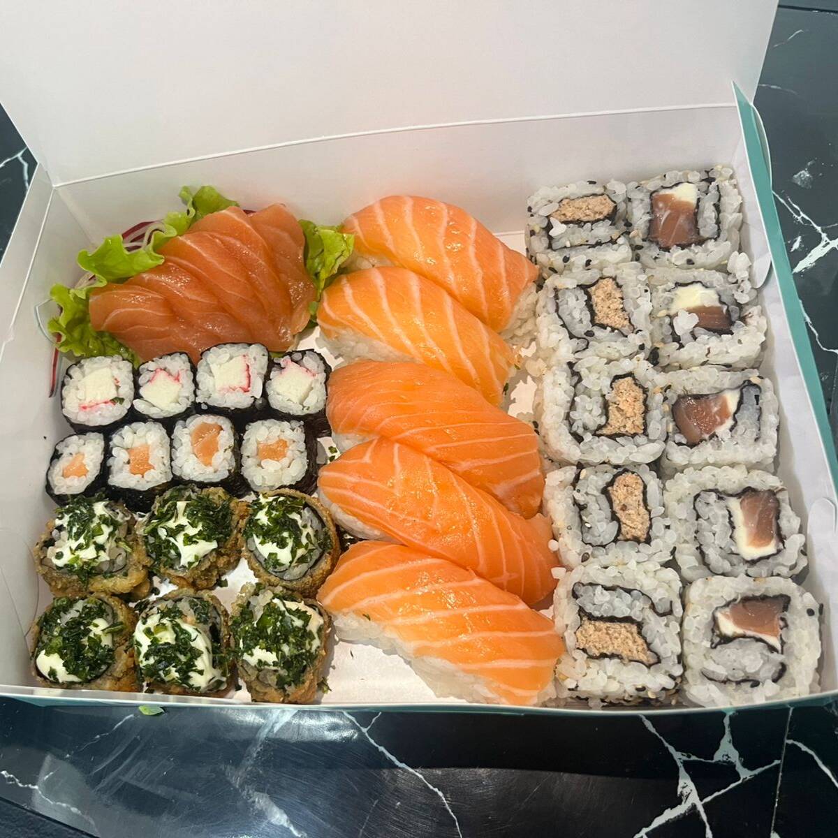 6 sashimis de salmão, 5 niguiris de salmão, 5 uramakis de salmão, 5 uramakis skin, 4 shakemakis de salmão, 4 kani makis e 6 hot rolls. Acompanha 2 hashis, 2 saches de molho shoyo e 2 saches de tarê.