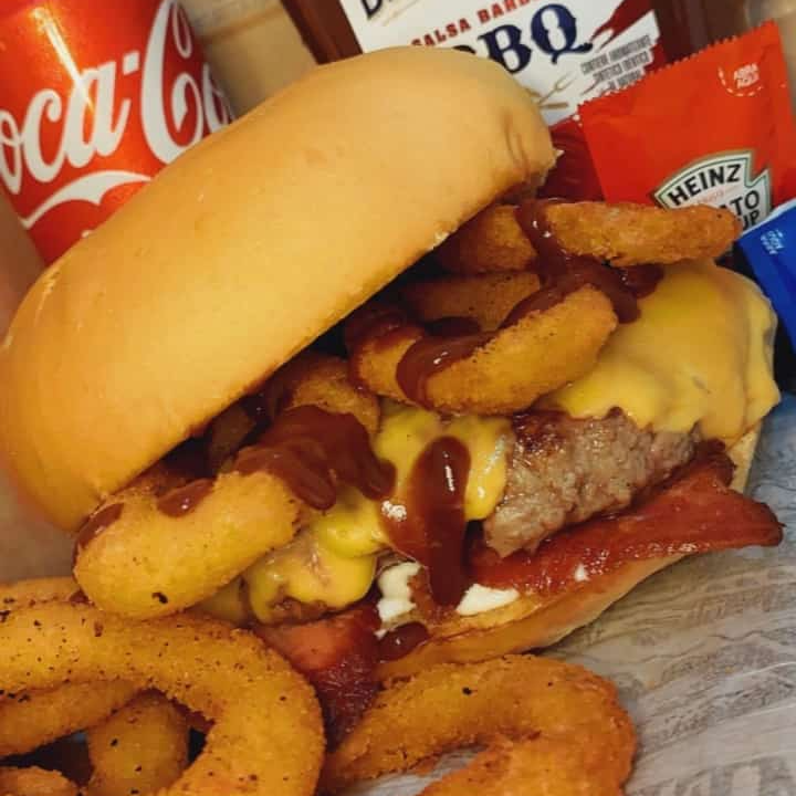 HAMBÚRGUER ARTESANAL DE 180 g, ACOMPANHADO COM QUEIJO PRATO DERRETIDO, TIRAS DE BACON CROCANTE, SERVIDOS COM ONION RINGS, EM NOSSO DELICIOSO PÃO BRIOCHE PRODUZIDO NA CASA, MAIONESE CASEIRA E BARBECUE.