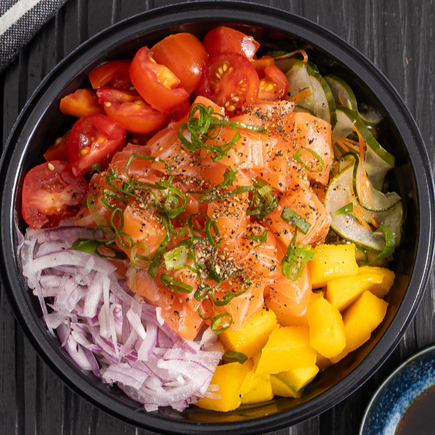 Cortes frescos de salmão cru sobre gohan, acompanhados de manga doce, pepino, cebola roxa e tomate cereja Refrescante, nutritivo e cheio de sabor oriental.