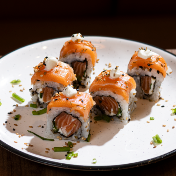 Arroz e gergelim por fora, recheado com salmão fresco cream cheese e cebolinha por dentro + uma camada de salmão por cima. *Não acompanha Molhos nem Hashi* (Valor de 5 unidades).